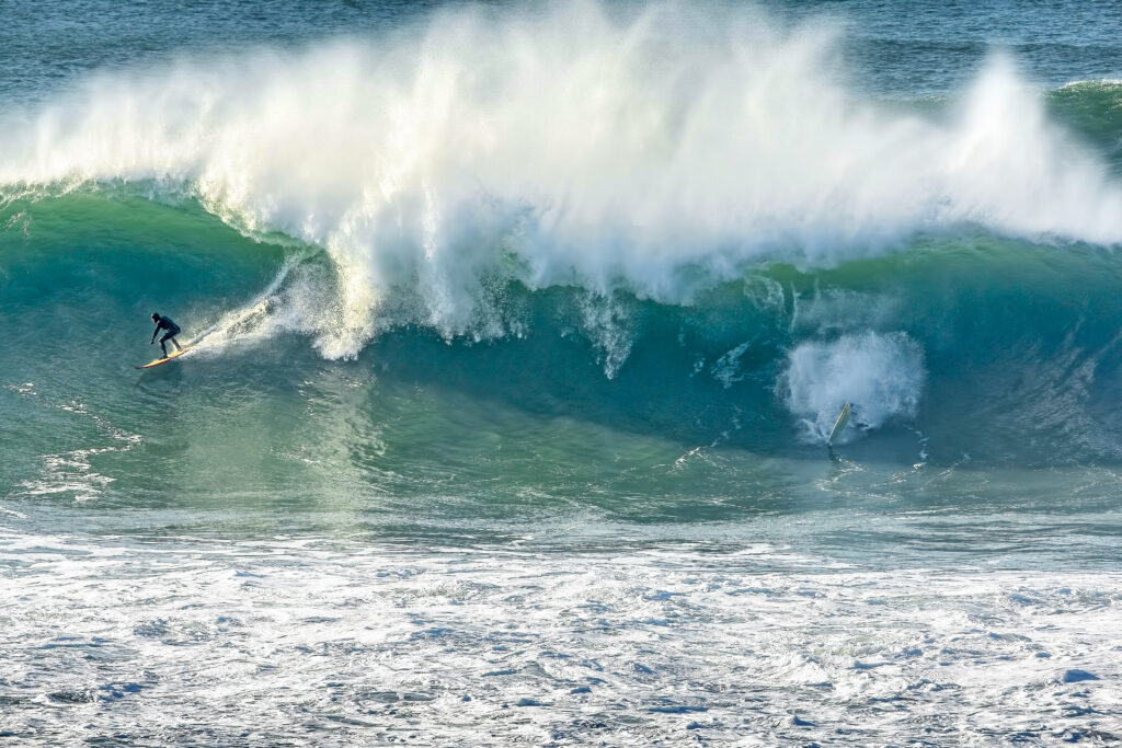 Surfer on a big wave at the Cribbar, Newquay, as another falls in the white water.